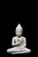 Buddha statue seated in light grey stone against a black background, copy space