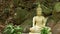 Buddha statue in wonderful garden. Lovely Buddha statuette placed near mossy boulders and green plants in beautiful