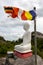 A Buddhist flag flies adjacent to a statue of Buddha.