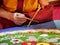Buddhist monk create drawing mandala with multicolor sands selective focus on hands