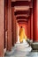 Buddhist monk walking along red wooden corridor of a monastery