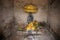 Buddhist shrine with stone statue of Buddha under yellow umbrella with offerings. Traditional buddhist altar