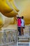 Buddists touching end of finger of large golden Buddha image