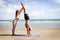 Buddy athlete woman, man do yoga and turns cartwheel on summer island beach, couple practicing yoga at seashore of tropical ocean