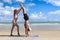 Buddy athlete woman, man do yoga and turns cartwheel on summer island beach, couple practicing yoga at seashore of tropical ocean