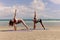 Buddy athlete woman, man doing yoga and stretching body on summer island beach, couple practicing yoga at seashore of tropical