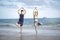 Buddy athlete woman and man doing yoga and stretching body on summer tropical island beach with blue sea, sport woman and man