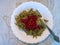 Budget cooked dish of brown buckwheat spaghetti with red currant berries. Plate and fork. Take out food. Cheap homemade food