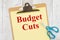 Budget Cut message on yellow lined paper with scissors on a clipboard