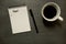 Budget list on gridded spiral notepad with cup of coffee, on slate table top - from above, minimal