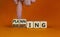 Budgeting and planning symbol. Businessman turns wooden cubes and changes the word planning to budgeting. Beautiful orange