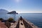 Budva - Tourist woman walking on wall of historical citadel of Budva with Scenic view over Saint Nicholas island