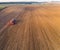 Bue tractor driving through vast golden-brown field and green farmland in the background. Sowing machine. Horizontal