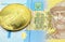 A bue and yellow one hryvnia note from Ukraine with a gold coin in macro