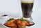 buffalo chicken wings barbecue or grill with red sauce in a gravy boat, beer in a tall glass with foam on a white