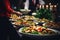 A buffet table displaying an assortment of food plates along with decorative candles., People group catering buffet food indoor in