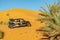 A buggy car parked in the Sahara desert sand dune with tourism pollution.