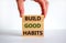 Build good habits symbol. Wooden blocks with words `build good habits`. Male hand. Beautiful white background, copy space.