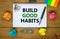 Build good habits symbol. Words `Build good habits` on white note. Wooden table, colored paper, paper clips, pen, coins. Busines