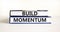 Build momentum symbol. Concept words Build momentum on books. Beautiful white table white background. Business and build momentum