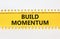 Build momentum symbol. Concept words Build momentum on yellow paper. Beautiful white background. Business and build momentum