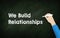 We Build relationships chalkboard with human hand. Building business relationship concept idea