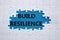 Build resilience symbol. White puzzle with words Build resilience. Beautiful blue background. Business and Build resilience