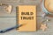 BUILD TRUST - inscription on a notebook and cup with coffee