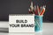 BUILD YOUR BRAND - inscription on a notebook with colored pencils