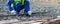 A Builder in a blue uniform, against the background of stones, takes long metal rods for the construction of concrete structures,