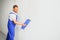 The builder carefully corrects the irregularities of the wall with a trowel. Builder in work clothes against a gray wall. Photo