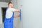 The builder carefully corrects the irregularities of the wall with a trowel. Builder in work clothes against a gray wall. Photo