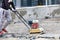 The builder compacts crushed stone with a gasoline vibratory compactor for subsequent laying of paving slabs