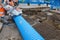 Builder cutting blue plastic duct pipe with petrol concrete saw and a diamond blade during water pipe repair works