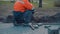 The builder is engaged in laying street tiles on the sidewalk in the city.