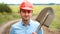 Builder, engineer or road worker is holding a shovel and looking at camera. Portrait of young caucasian man in shirt and