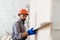 Builder at facade plastering work during industrial building with putty knife float