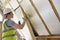 Builder Fitting Insulation Into Roof Of New Home