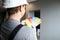 Builder in helmet holds color palette near wall