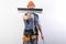 The builder hides his face behind a spatula. In work clothes and hard hat. On a light gray background