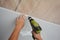 A builder is installing plastic ceiling panel, white PVC bathroom ceiling cladding in a bathroom using an electric screwdriver to