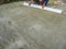 The builder levels the surface of a dry cement-sand base for laying paving slabs. Long aluminum plate in male hands. Construction