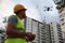 Builder operating drone with remote control at construction site. Aerial photography