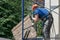 A builder in an orange helmet works on scaffolding. Repair of the facade of the building, wall painting, plastering and wall