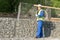 Builder in overalls carries a large skein of wire on his shoulder, side view