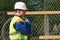 Builder in overalls carries a large skein of wire on his shoulder, side view close-up