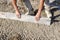 Builder placing edging pin kerb on semi-dry concrete using a string line to keep them straight during construction