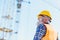 Builder in reflective vest and hardhat standing at construction site,