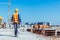 Builder in reflective vest and hardhat walking across a construction site with rolls of plans