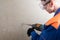 Builder in safety glasses and helmet drills a wall with a perforator, side view, left space for inscription